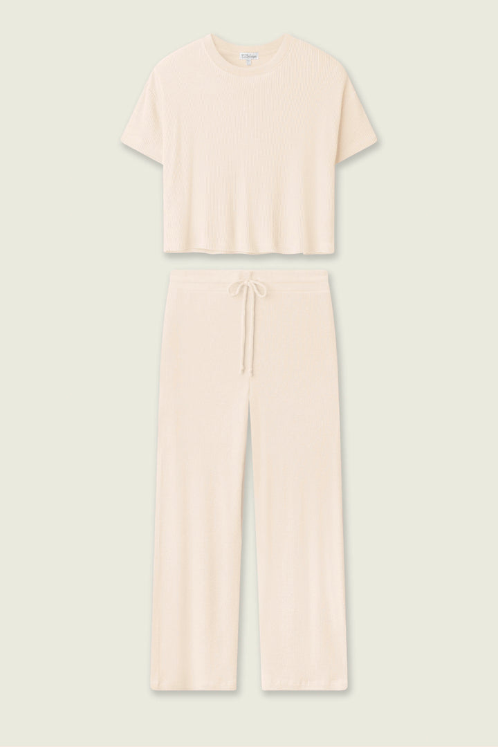 The P.J. Salvage Textured Essentials Stone Long PJ Set features a cream rib knit loungewear set with a short-sleeve cropped top and wide-leg, drawstring waist pants, shown against a plain light background.