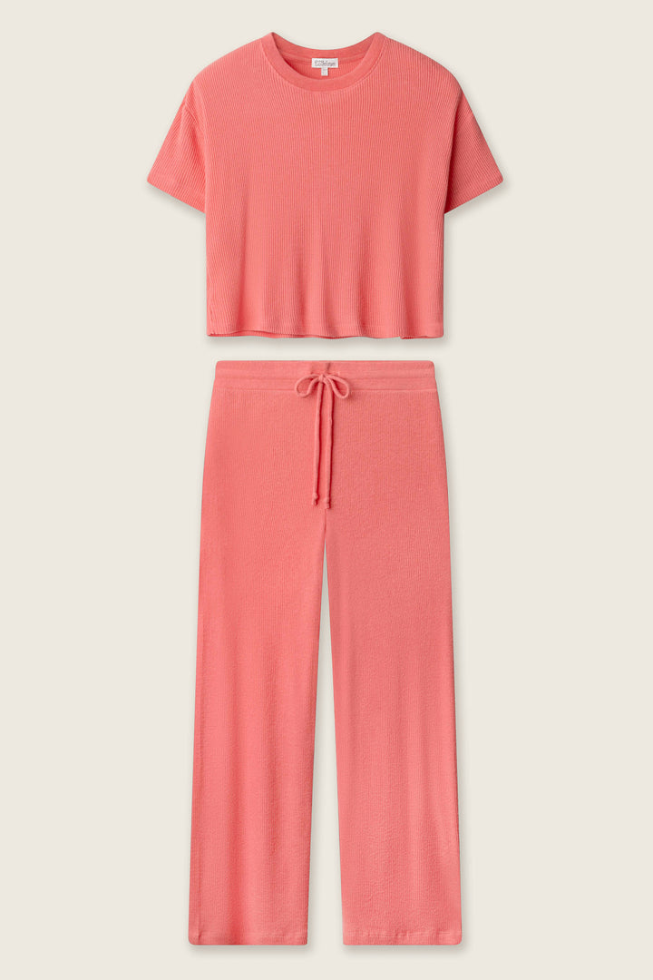 The P.J. Salvage Textured Essentials Sunset Rose Long PJ Set features a textured rib short-sleeve, cropped pink top and wide-leg drawstring pants, as shown on a plain light background.