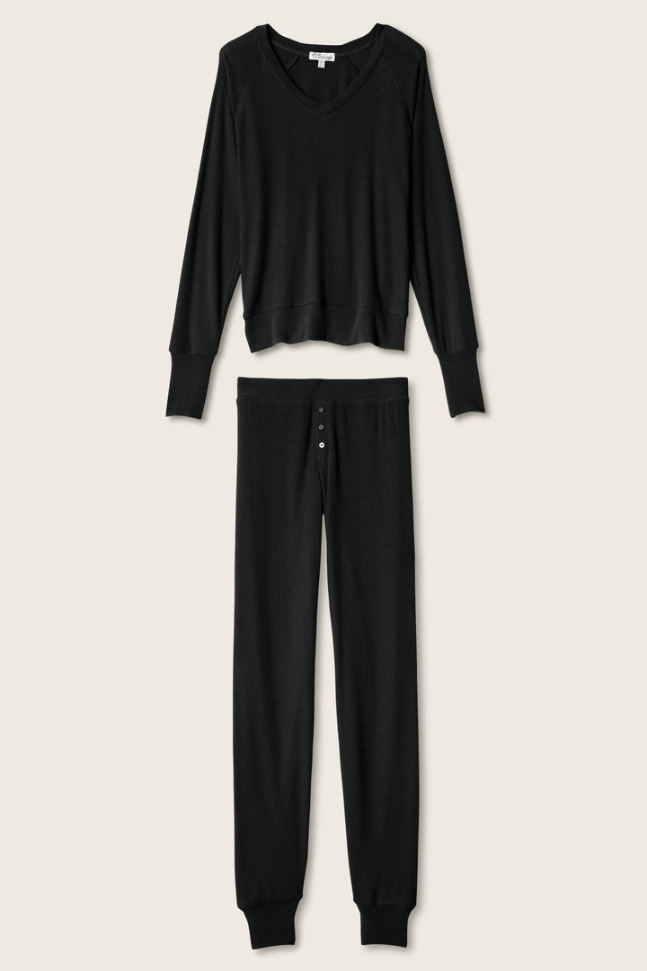 The P.J. Salvage Textured Essentials Black Long PJ Set features a soft ribbed peachy jersey V-neck top and button-fly lounge pants, shown against a light beige background.