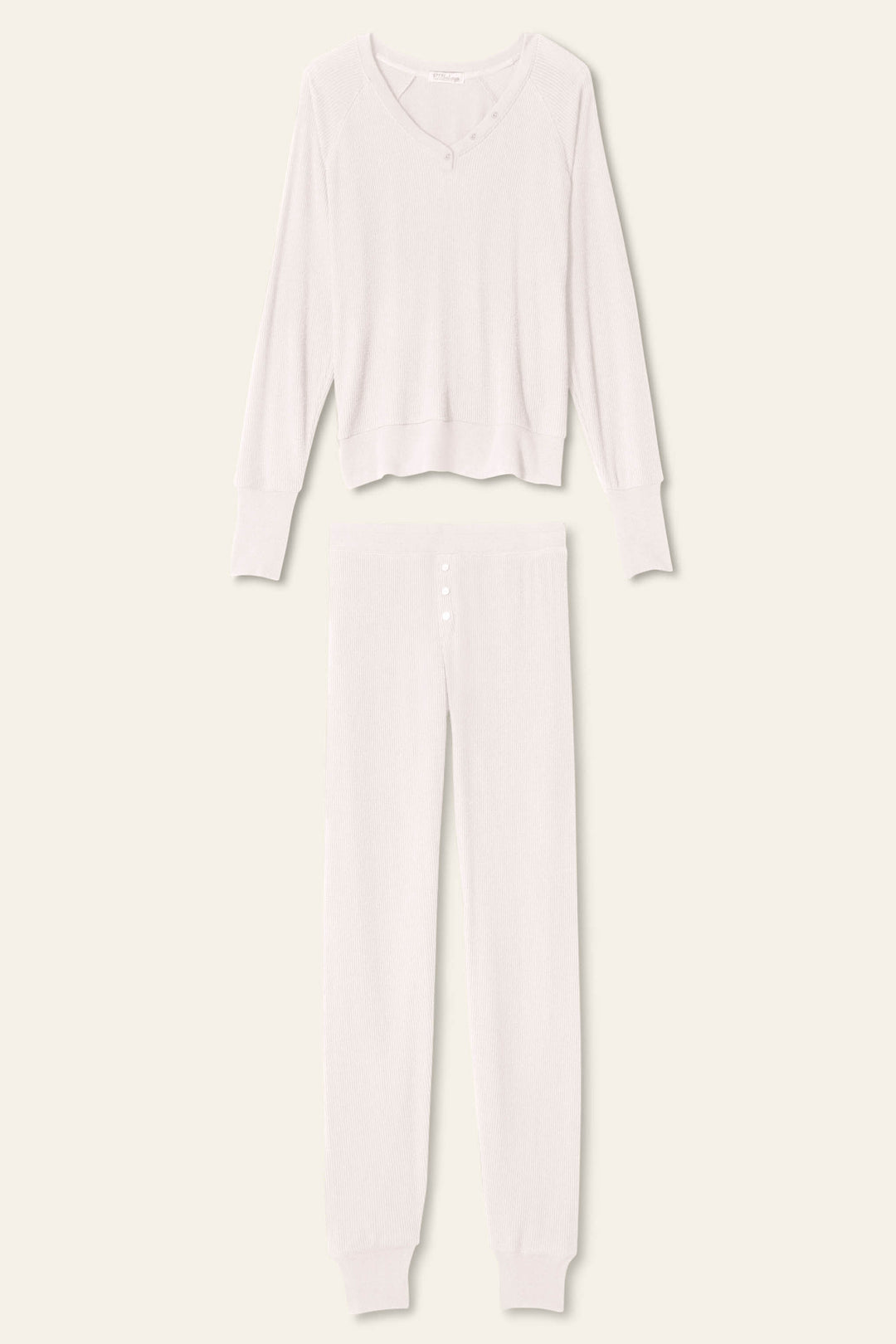 Introducing the P.J. Salvage Textured Essentials Stone Lounge Set—a coordinating light beige knit ensemble, featuring a long-sleeve Henley top with a scoop neckline and button detailing, paired with matching long pants with a buttoned front and cuffed ankles. This set is crafted from soft rib peachy jersey and beautifully displayed flat on a neutral background.