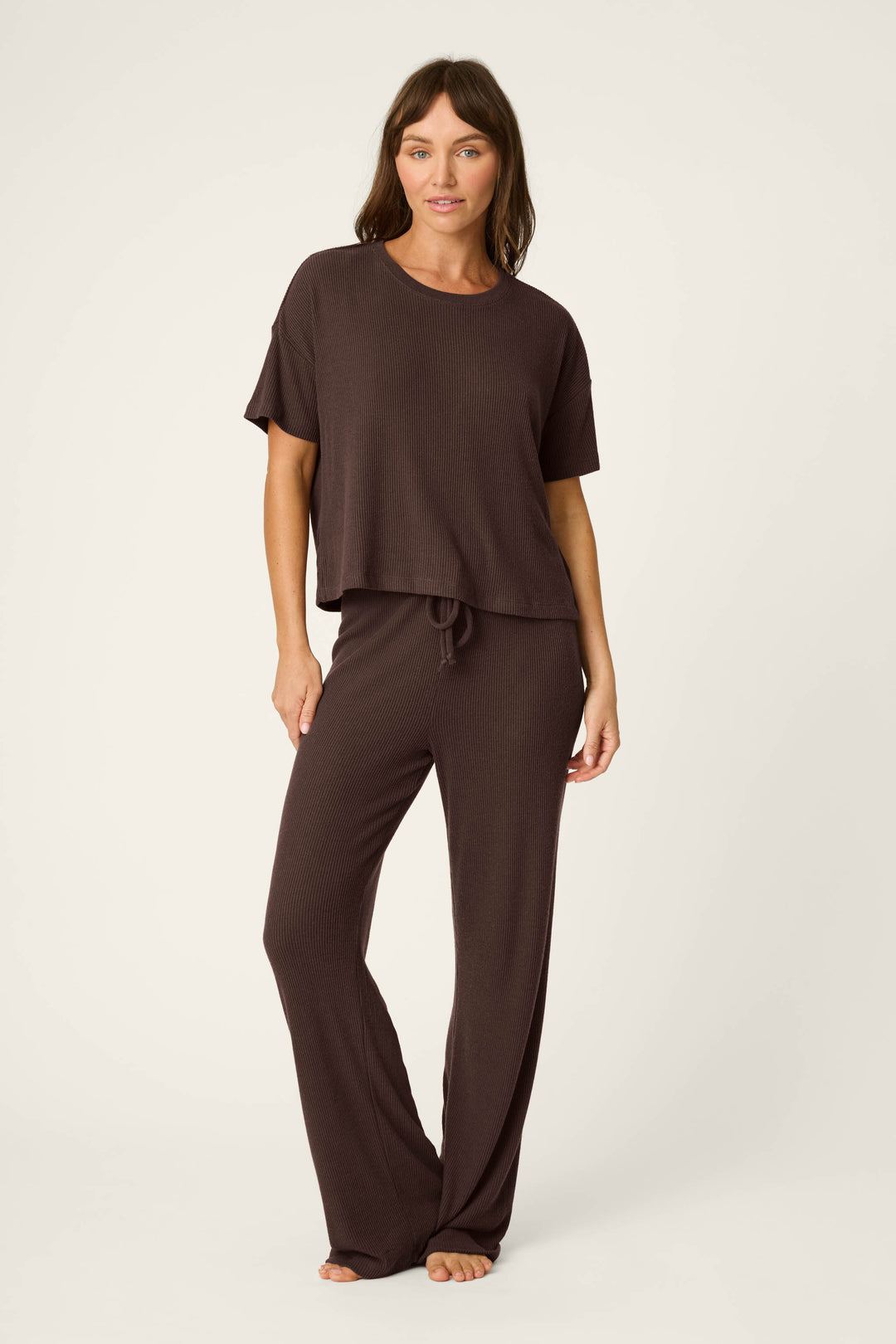 A woman stands barefoot against a plain background, wearing the P.J. Salvage Textured Essentials Chocolate Brown Short Sleeve Top and matching wide-leg pants.