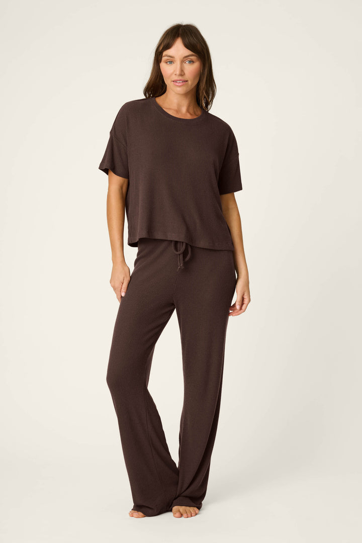 A woman stands barefoot against a plain background, wearing the P.J. Salvage Textured Essentials Chocolate Brown Short Sleeve Top and matching wide-leg pants.