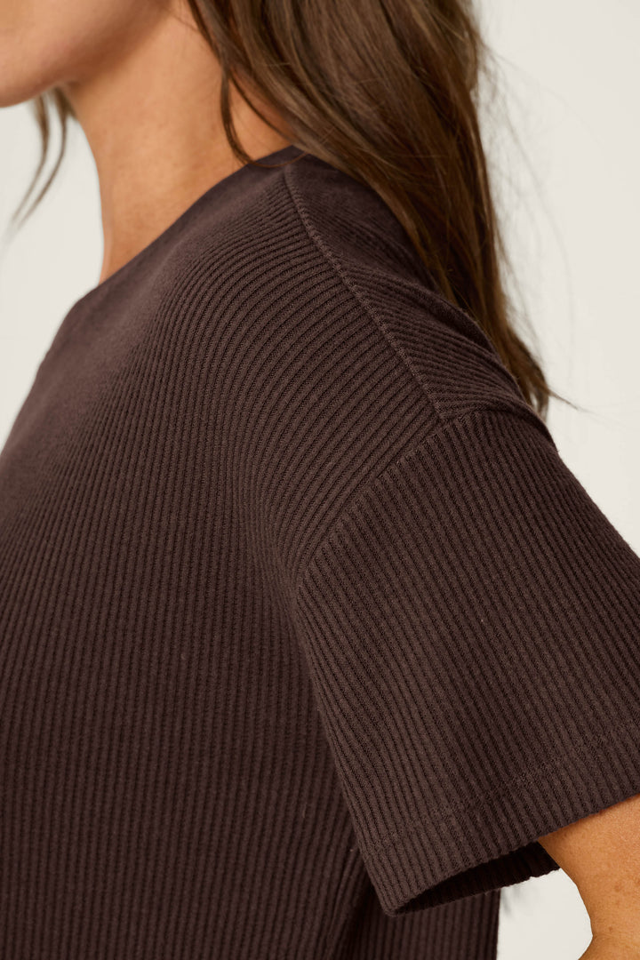 A close-up side view of a person wearing the P.J. Salvage Textured Essentials Chocolate Brown Short Sleeve Top, showing only part of their face, hair, shoulder, and upper arm.