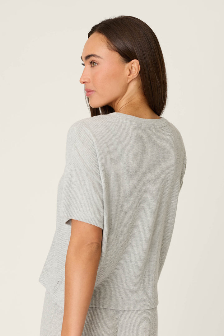 A woman with long, straight brown hair wears the P.J. Salvage Textured Essentials Heather Grey Short Sleeve Top. She faces away, looking over her shoulder against a plain, light background.