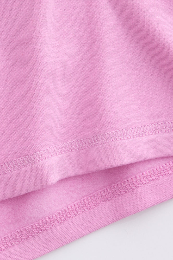 Pastel pink long sleeve top with white whipstitching at raglan seams. B&ed hem.