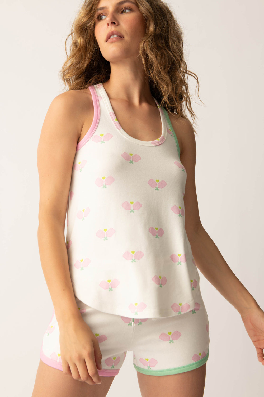 Women's racer back tank top in ivory-pink racket printed peachy with pink & green contrast binding.