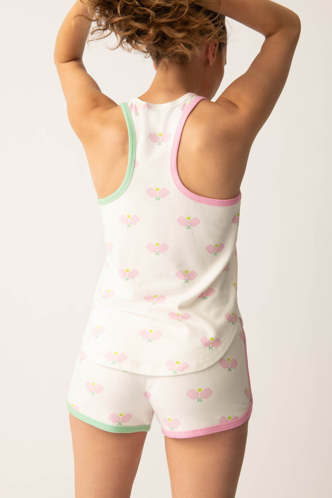 Women's racer back tank top in ivory-pink racket printed peachy with pink & green contrast binding.