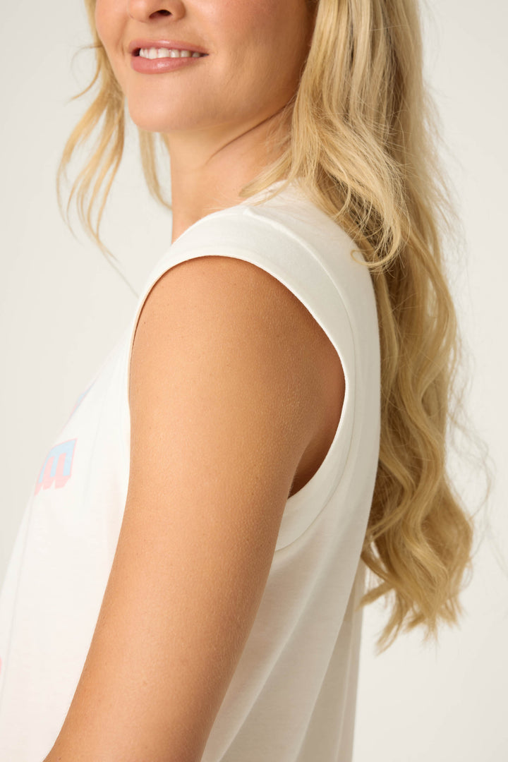 Close-up side view of sleeveless ivory muscle tee showing clean armhole finish and soft cotton texture.