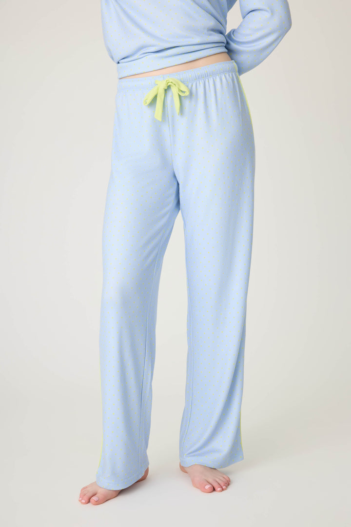 A person stands barefoot in P.J. Salvage’s Beautiful Life Polka Dot Open Leg Pant, light blue with a yellow drawstring and small dots, shown from the waist down with part of a matching top visible.