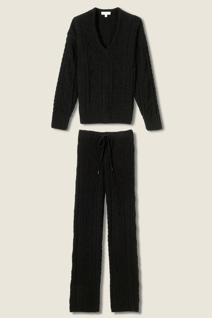 The P.J. Salvage SOLID PJ SET COZY CHENILLE CABLE KNIT, shown in black on a neutral background, features a V-neck long sleeve sweater and relaxed drawstring pants. Both pieces have a cozy cable knit pattern.