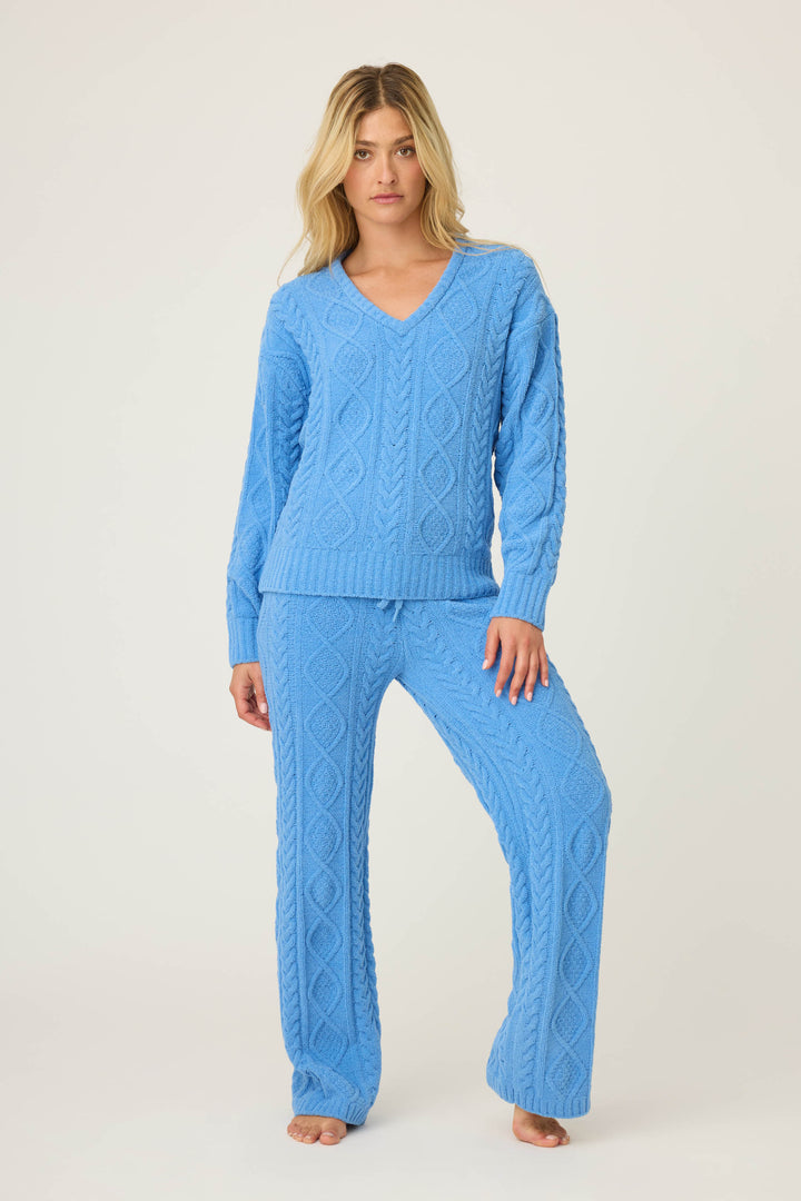 A woman stands barefoot against a plain background, wearing the SOLID PJ SET COZY CHENILLE CABLE KNIT by P.J. Salvage in light blue. She faces forward with a neutral expression, her left hand resting on her thigh.