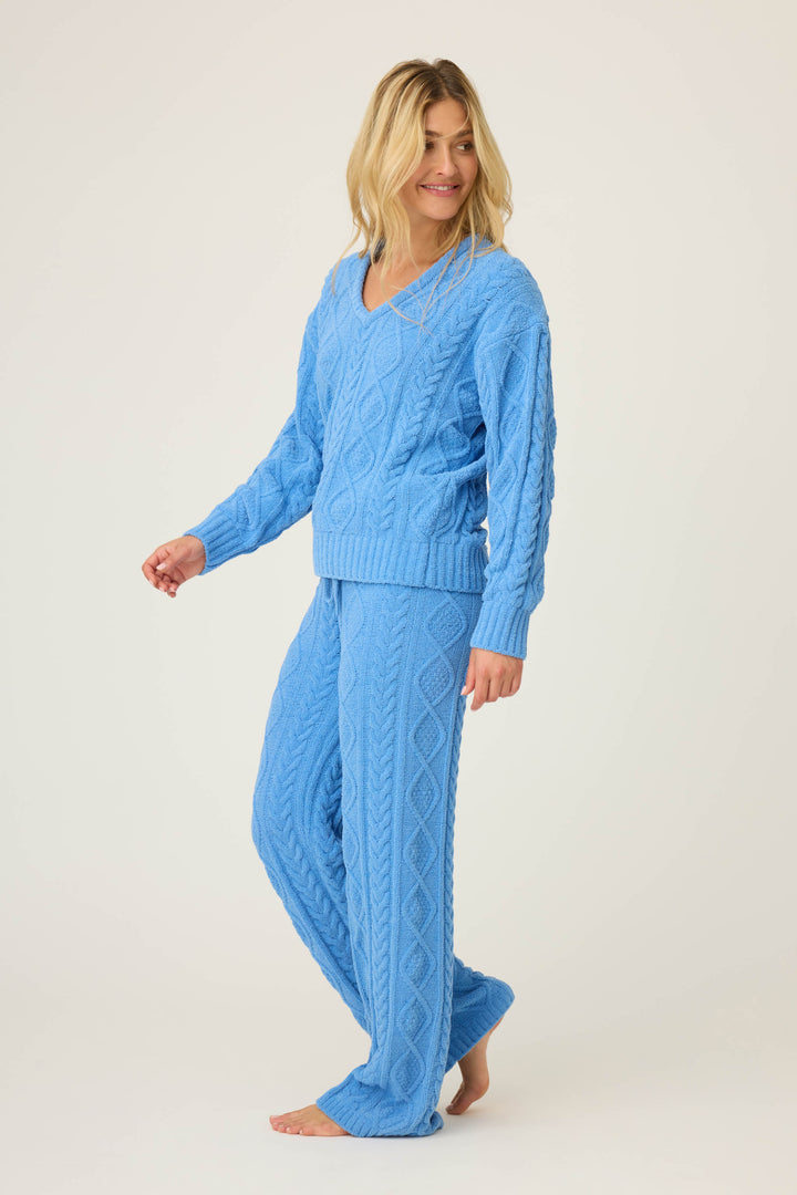 A person with long blonde hair models the P.J. Salvage SOLID PJ SET COZY CHENILLE CABLE KNIT in light blue, standing barefoot on a plain background, looking slightly to the side and smiling.