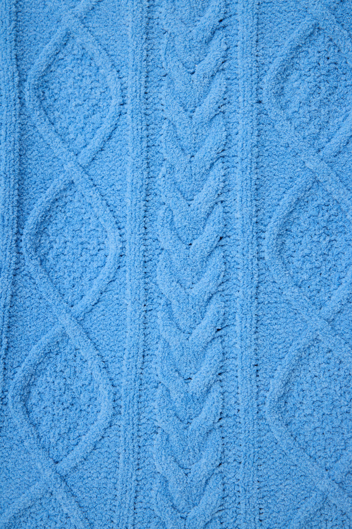 Close-up of the SOLID PJ SET COZY CHENILLE CABLE KNIT by P.J. Salvage, showcasing blue textured fabric with a raised cable knit pattern, braided central design, and diamond shapes on each side.