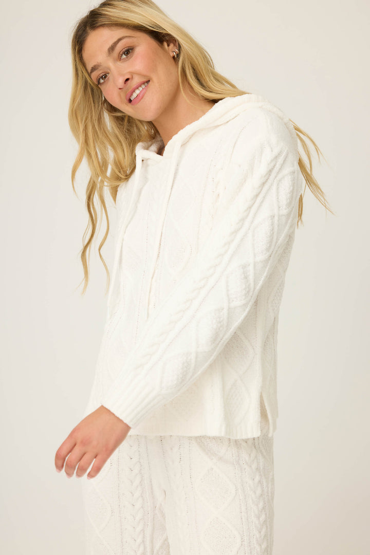 A woman with long blonde hair models the P.J. Salvage SOLID PJ SET COZY CHENILLE CABLE KNIT, featuring a white textured hoodie and matching pants, while smiling against a plain light background.