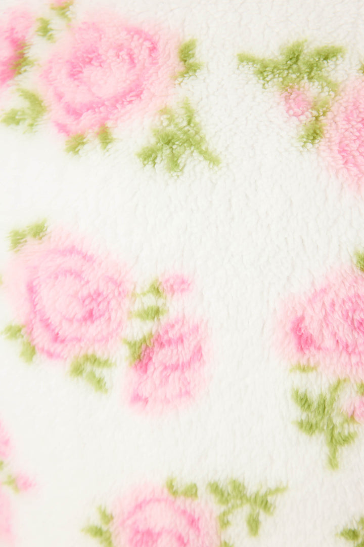 A close-up of the Lets Get Cozy Floral Print Robe by P.J. Salvage shows soft, white, fuzzy fabric with a delicate print of pink roses and green leaves, creating a cozy and gentle look.