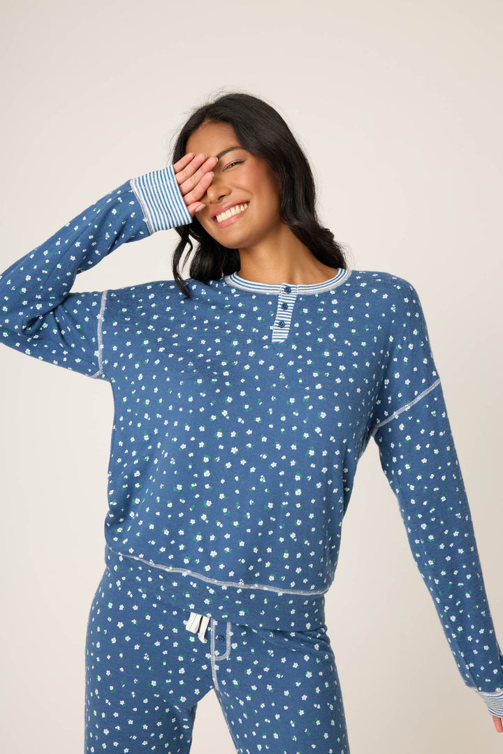 A person in the P.J. Salvage Cozy Life Floral Long Sleeve Top stands against a plain background, smiling with one hand covering part of their face.