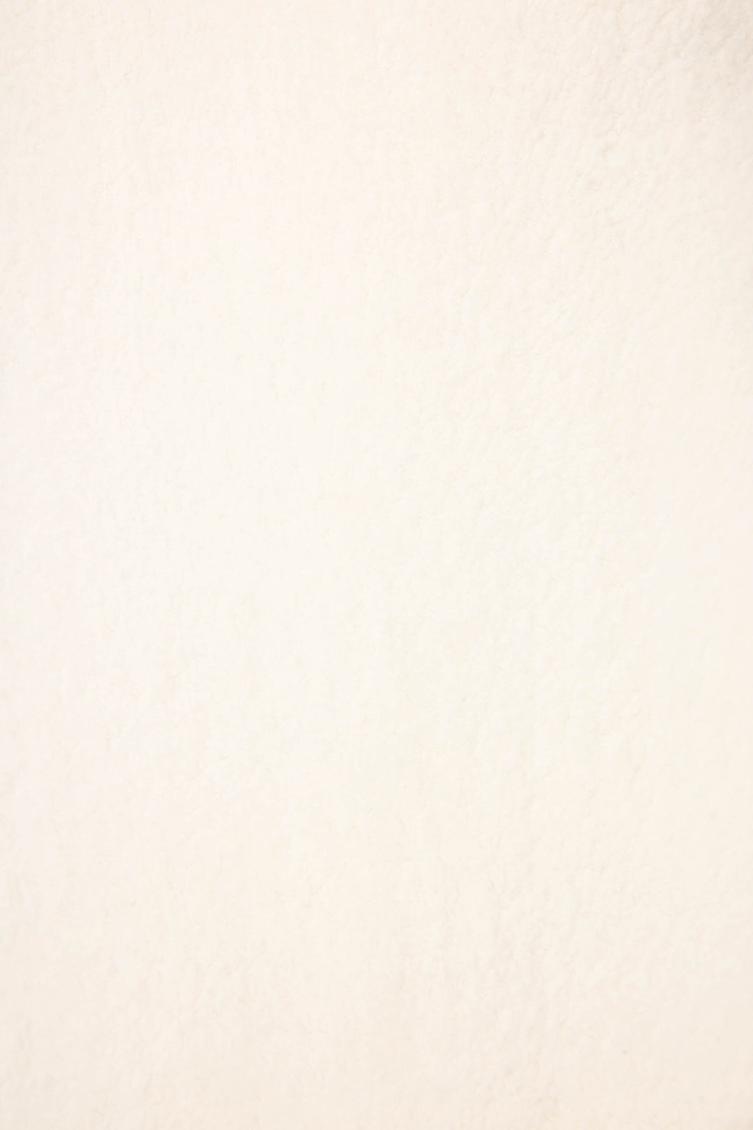 A close-up of the Cozy Life Floral Quarter-Zip Fleece Sweatshirt by P.J. Salvage shows its lightly textured, off-white surface, similar to paper or a subtle wall, with no distinct patterns or additional colors visible.