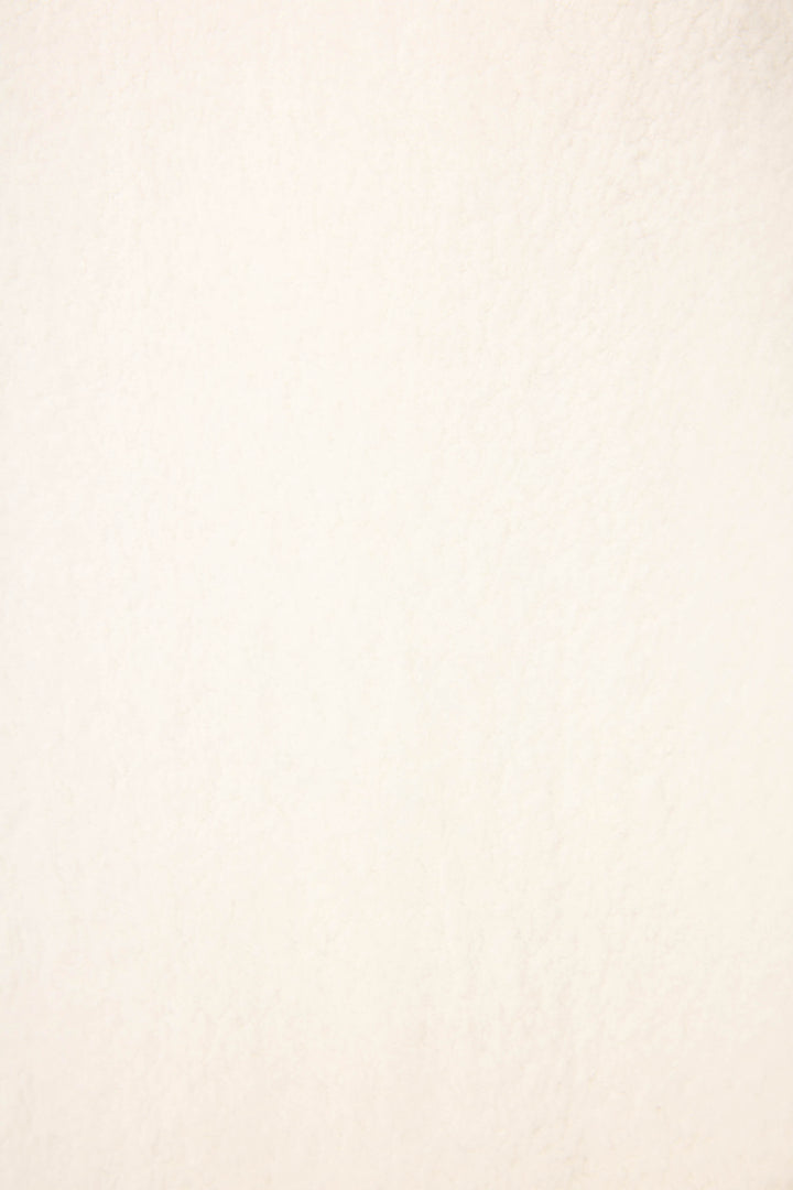 A close-up of the Cozy Life Floral Quarter-Zip Fleece Sweatshirt by P.J. Salvage shows its lightly textured, off-white surface, similar to paper or a subtle wall, with no distinct patterns or additional colors visible.