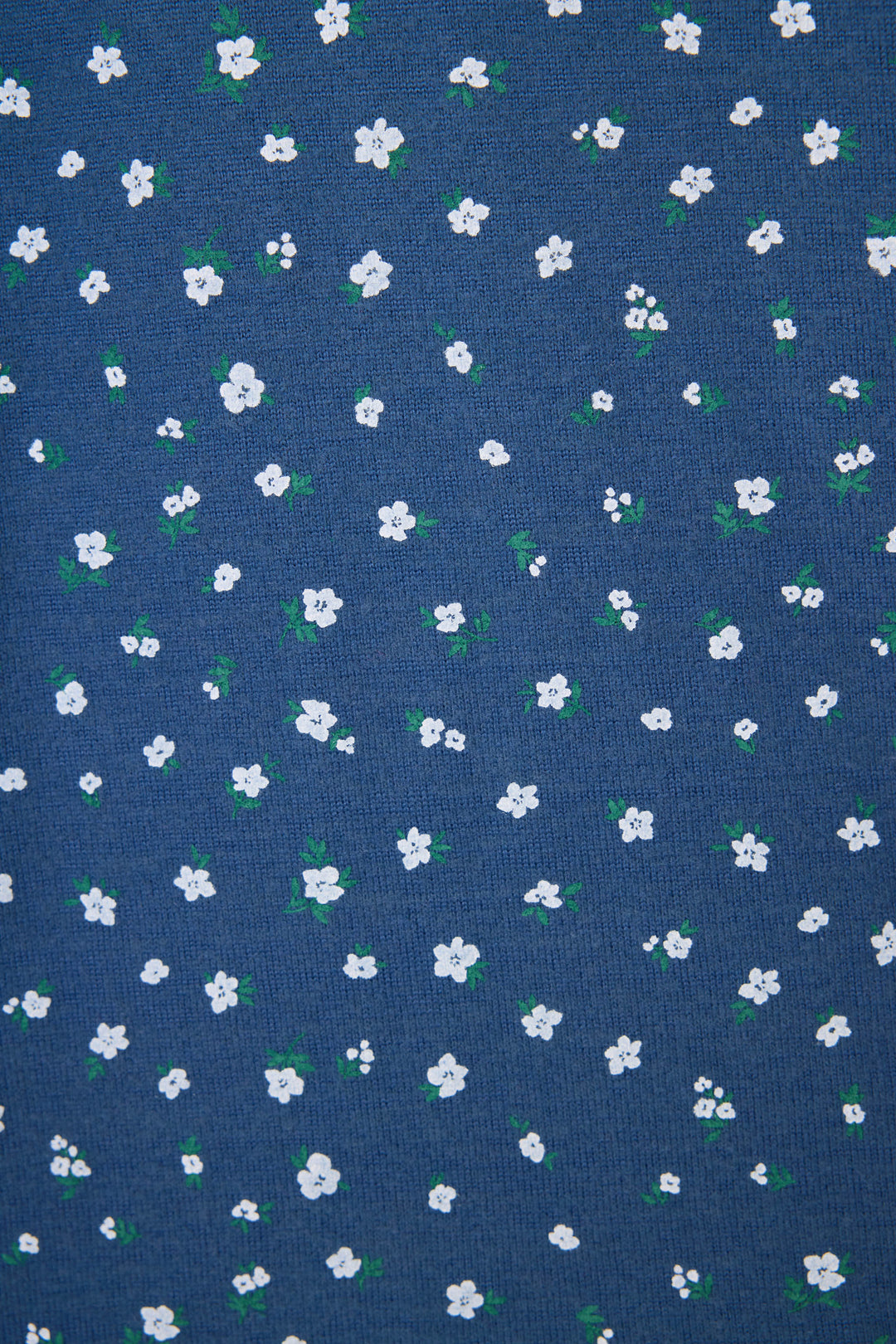 A close-up of the Cozy Life Floral Short by P.J. Salvage, made from blue fabric decorated with small white flowers and green leaves evenly scattered across the surface.