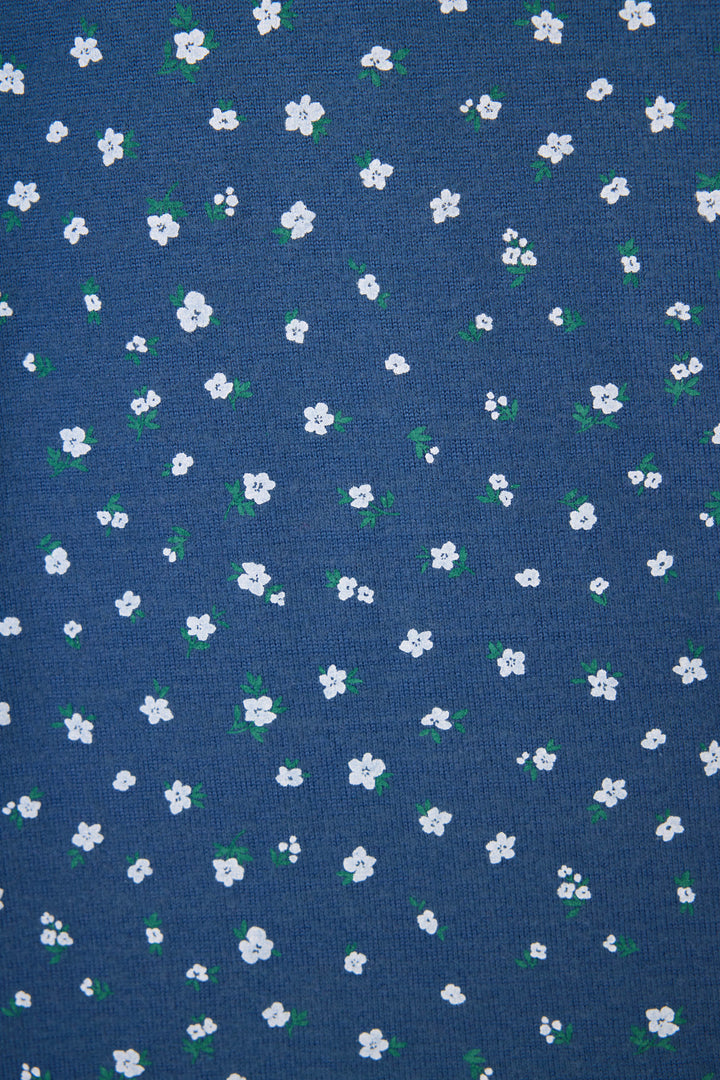 A close-up of the Cozy Life Floral Short by P.J. Salvage, made from blue fabric decorated with small white flowers and green leaves evenly scattered across the surface.
