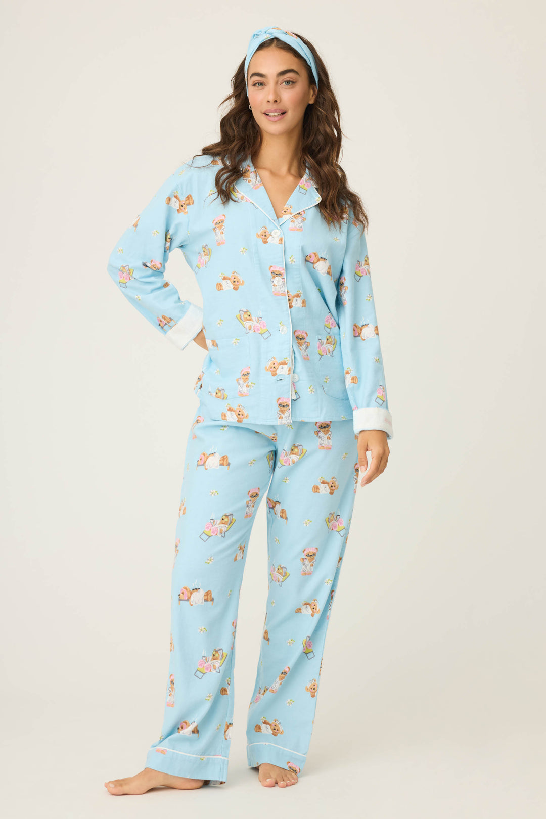 A woman with long, wavy dark hair and bare feet poses against a plain background wearing the P.J. Salvage Beary Cute Bear Print Flannel PJ Set with a matching headband.