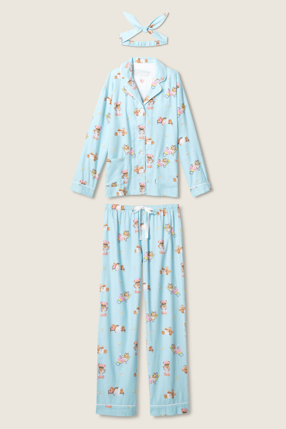The P.J. Salvage Beary Cute Bear Print Flannel PJ Set includes a light blue button-up long sleeve top, full-length pants, and matching headband with playful teddy bear print, displayed flat on a neutral background.