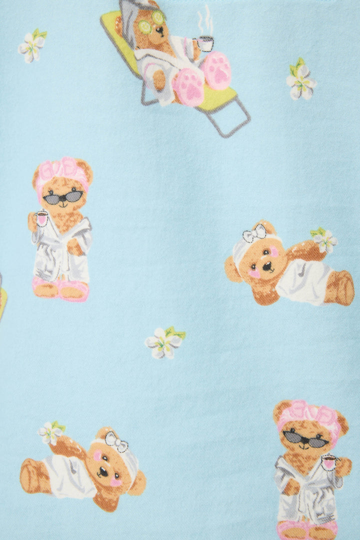 The Beary Cute Bear Print Flannel PJ Set by P.J. Salvage features a light blue fabric with cartoon bears in spa robes, cups in hand, relaxing among spa accessories and white flowers. Perfect for lounging in comfy and adorable style.