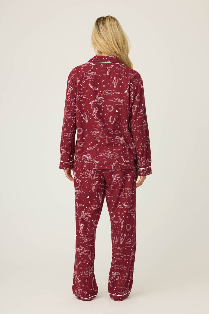 A person with long blonde hair faces away, wearing the P.J. Salvage 3-Piece Set PAISLEY PJ SET FLANNELS featuring a matching burgundy top and pants with white paisley prints. The background is plain and light-colored.