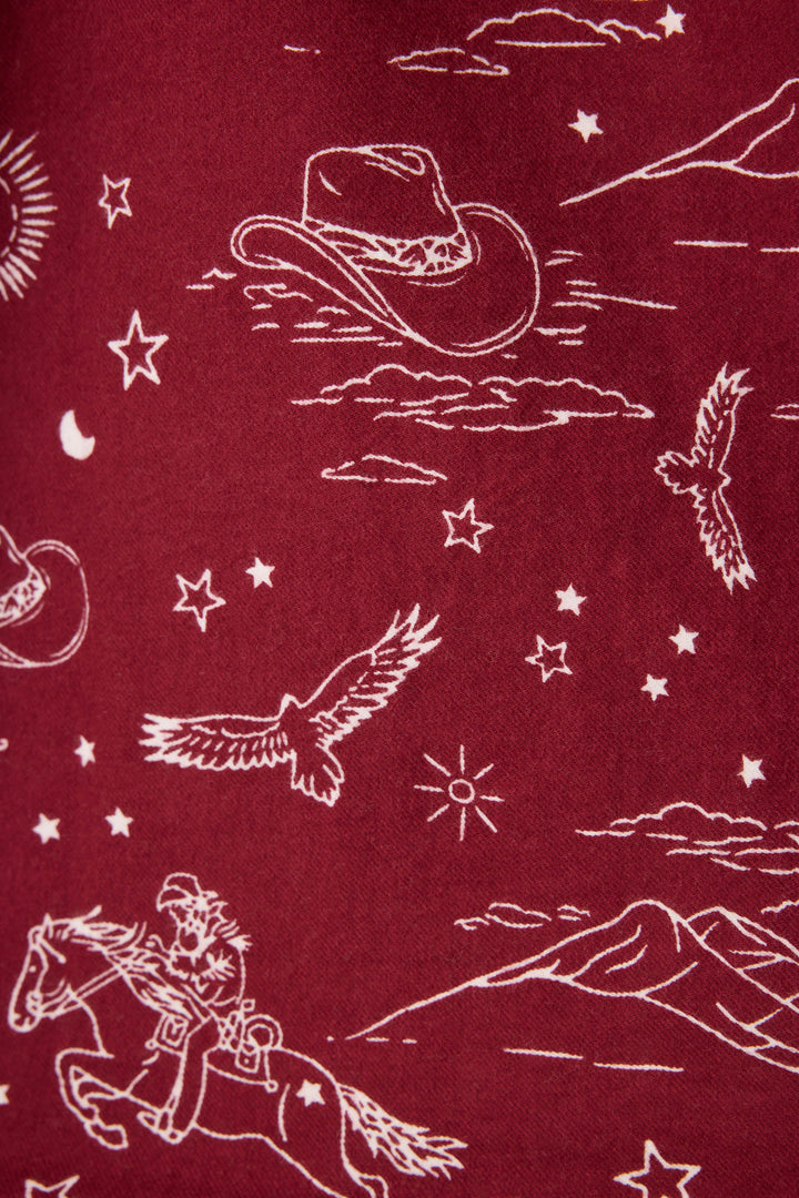 The 3-Piece Set PAISLEY PJ SET FLANNELS by P.J. Salvage features maroon fabric with white Western-themed illustrations, including cowboy hats, stars, clouds, mountains, a horseback rider, birds, the sun, and the moon.
