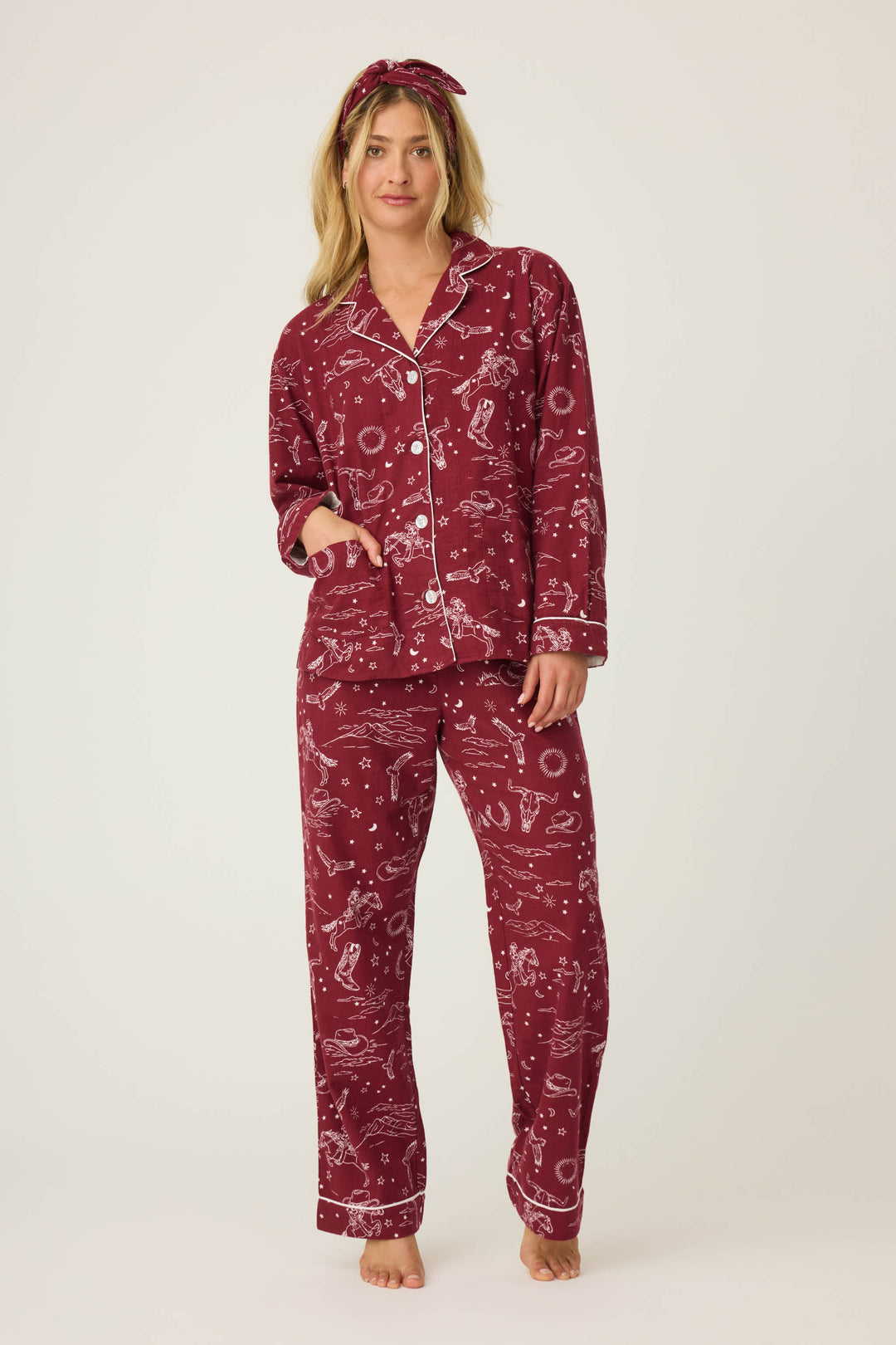 A woman stands barefoot against a plain background, wearing the P.J. Salvage 3-Piece Set PAISLEY PJ SET FLANNELS with white prints and piping, her hand in her pocket and a matching headband on.