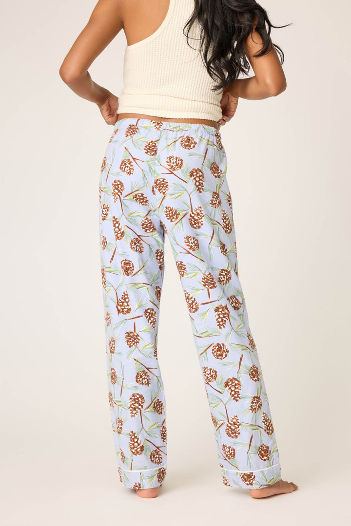 A person stands barefoot facing away, wearing P.J. Salvage’s Feelin' Pine Pinecone Print Flannel Pant and a ribbed off-white tank top, set against a plain background.