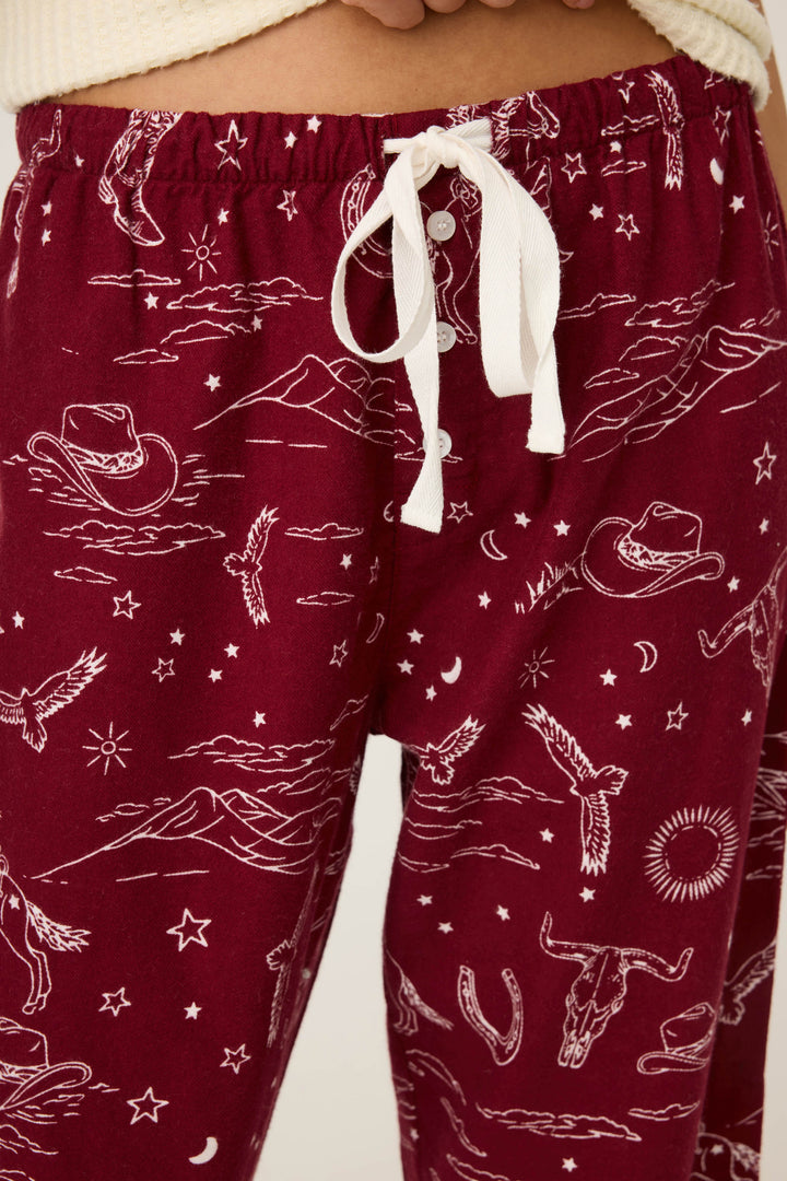 Close-up of P.J. Salvage DOGS PANT FLANNELS in port, showcasing maroon pajama pants with a white drawstring and playful pattern. A cream-colored top is partially visible.