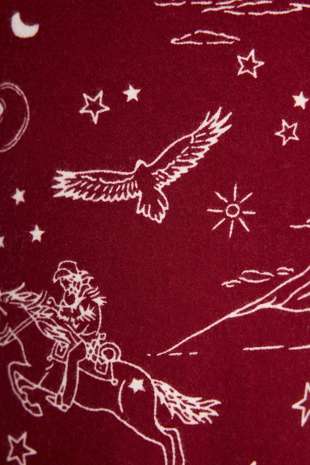 White line drawing on dark red DOGS PANT FLANNELS - port by P.J. Salvage, featuring a cowboy on horseback, an eagle, stars, clouds, and a sun in a Western-themed pattern.