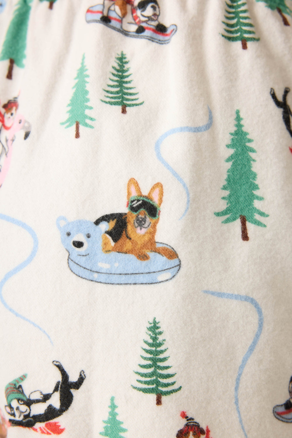 Sleigh All Day Winter Print Flannel Shorts by P.J. Salvage feature illustrated dogs in winter pajamas, sledding and lounging on pool floats among pine trees—a cozy design perfect for flannel boxer shorts.