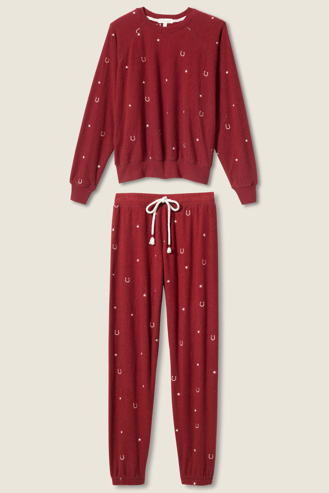 The P.J. Salvage Pant Set HORSE SHOE PJ SET HOLD YOUR HORSES features a dark red, long-sleeve crew-neck top and drawstring pants with small white horseshoe patterns and an elastic waistband.