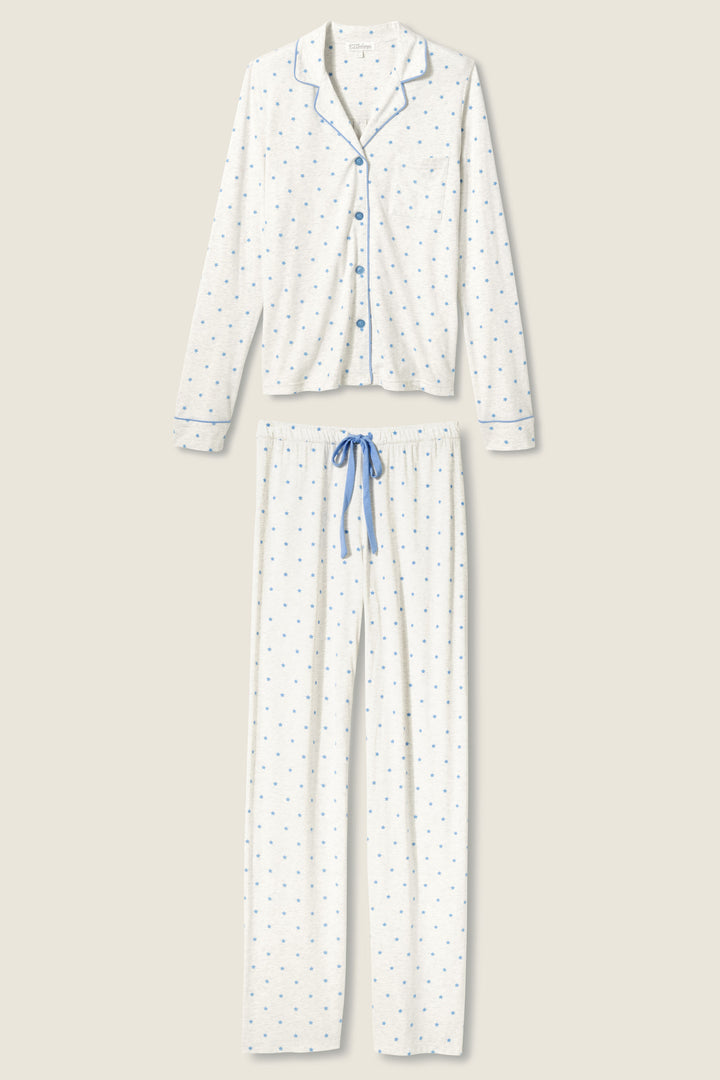 The P.J. Salvage Pant Set FLOCKING NOTCH COLLAR PJ SET LADY LUCK features a white two-piece pajama set with a long-sleeve, button-up top and matching pants. Both have a small blue pattern, blue trim and buttons, plus a blue drawstring waist on the pants.