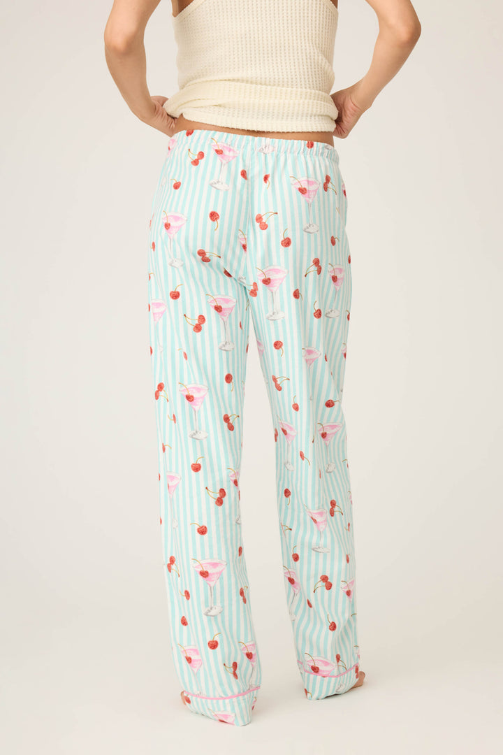 A person is shown from the back wearing P.J. Salvages DOGS PANT FLANNELS, featuring a cream sleeveless top and light blue pajama pants with white stripes and playful cherry and cocktail glass motifs against a plain background.