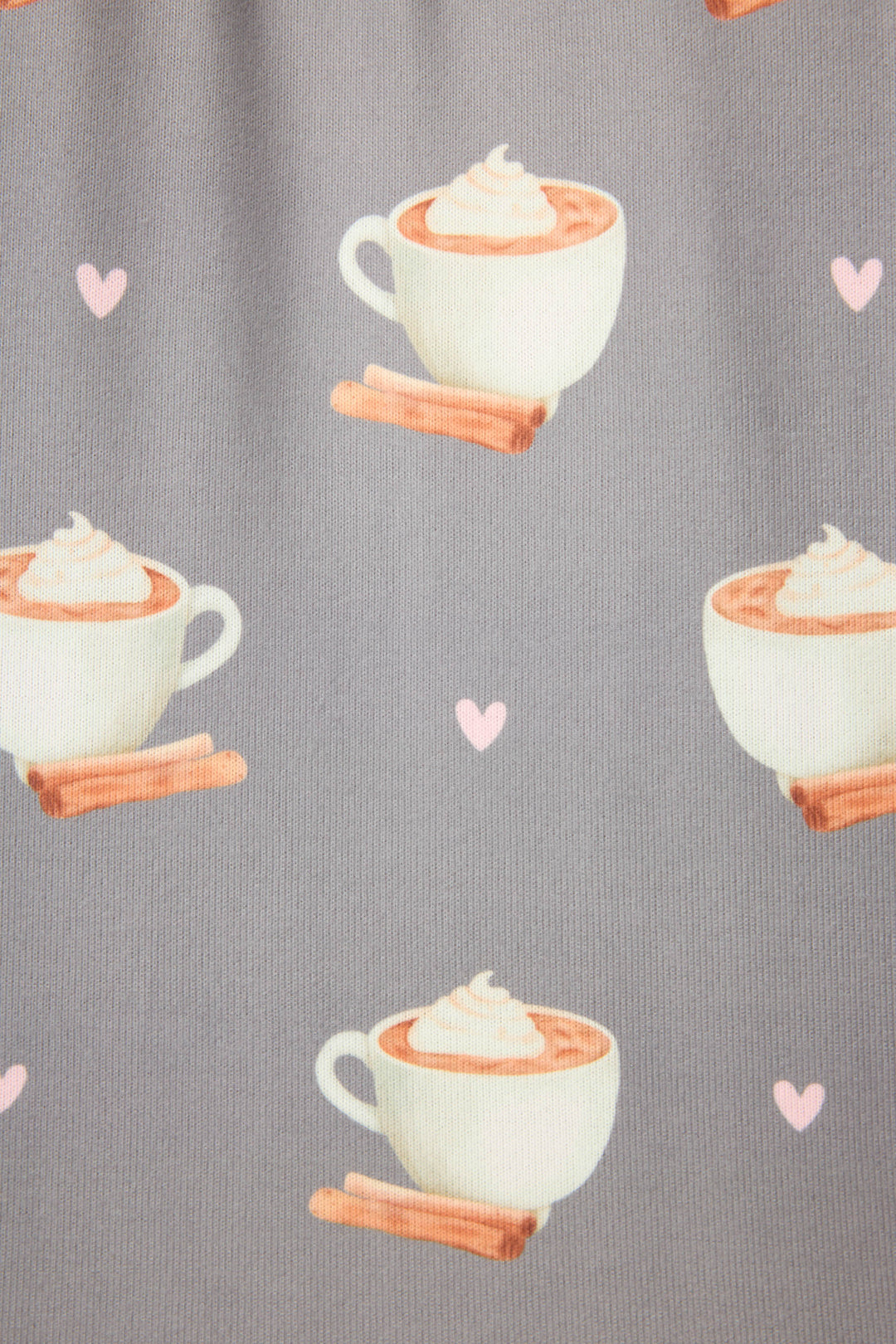 The P.J. Salvage Love You A Latte Coffee Print Long Sleeve Top features a playful pattern of white cups with whipped topping, resting on cinnamon sticks and accented by pink hearts on a gray background.