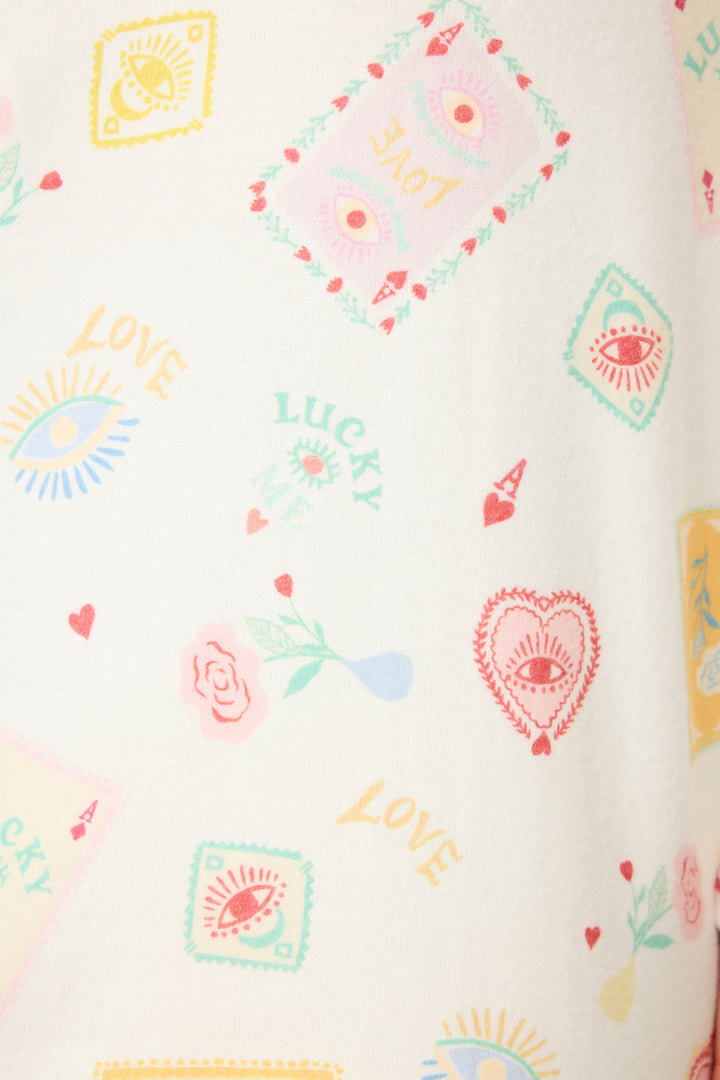 The P.J. Salvage Pant Set LUCKY PJ SET LUCKY ME features white fabric with colorful prints—eyes, hearts, roses, and the words LOVE and LUCKY ME in playful fonts and pastel shades.