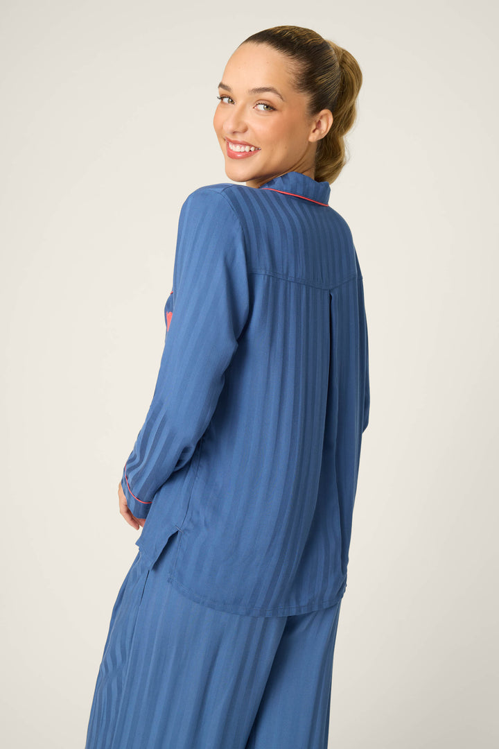 A person, turned slightly to the side and smiling over their shoulder, wears the P.J. Salvage La Rose Striped Long Sleeve Top with matching pants against a plain, light background.