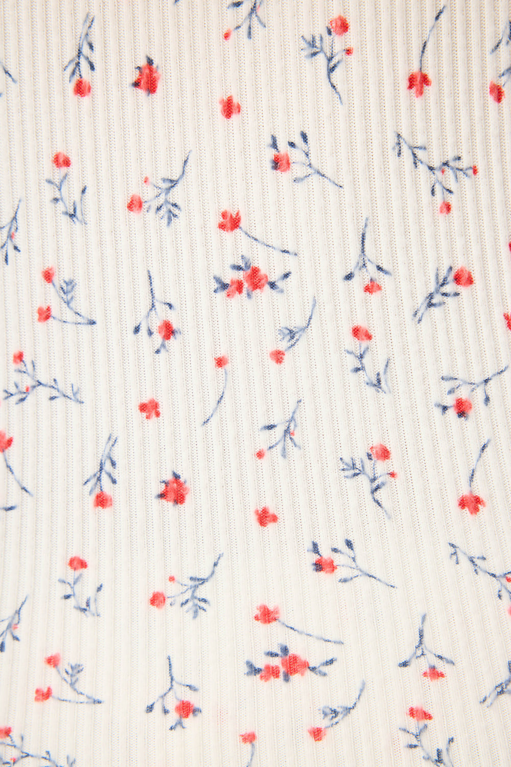 A close-up of the FLORAL PJ SET LA ROSE by P.J. Salvage shows ribbed white fabric with small red flowers and blue stems scattered across the surface.
