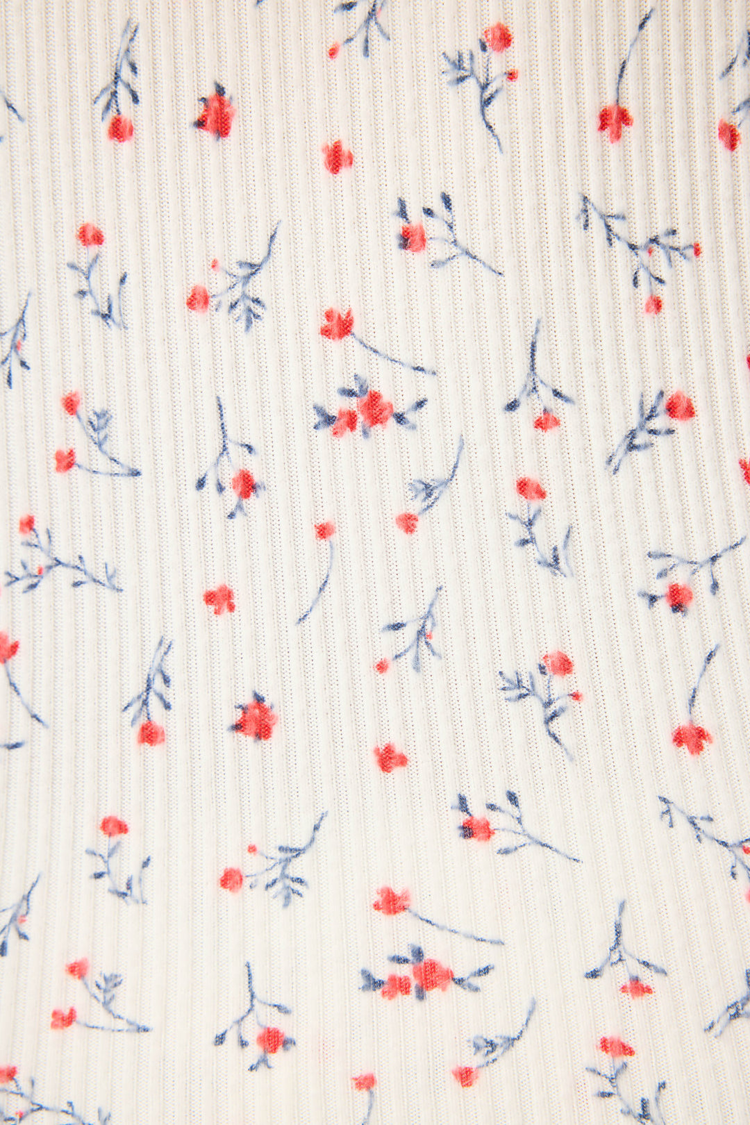 A close-up of the FLORAL PJ SET LA ROSE by P.J. Salvage shows ribbed white fabric with small red flowers and blue stems scattered across the surface.