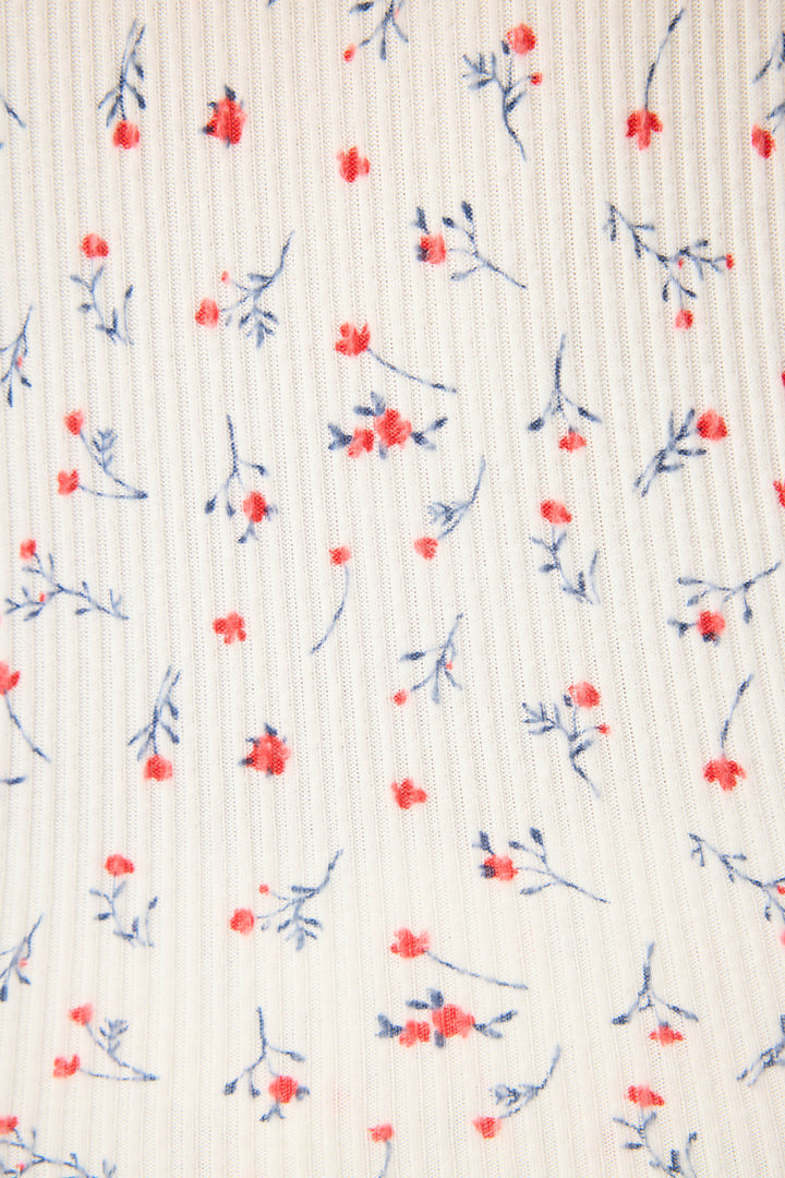 A close-up of the FLORAL PJ SET LA ROSE by P.J. Salvage shows ribbed white fabric with small red flowers and blue stems scattered across the surface.