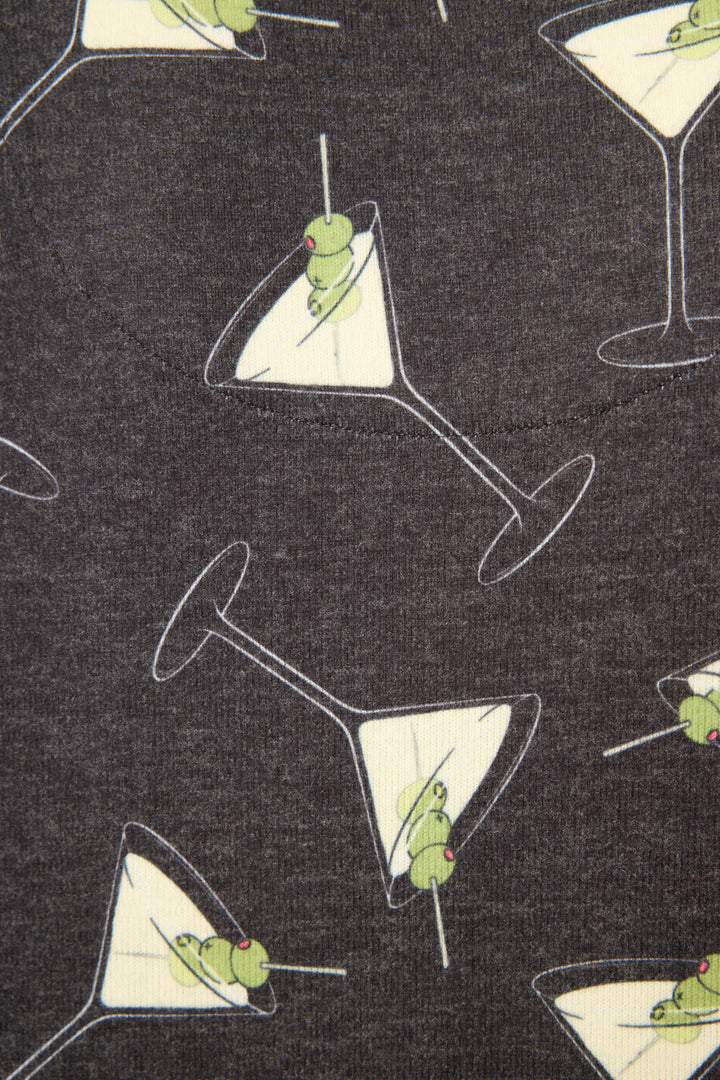 The Merrier With A Martini Long Sleeve Top by P.J. Salvage features dark fabric with a repeating pattern of martini glasses, each filled with a yellowish liquid and green olives, oriented in various directions.