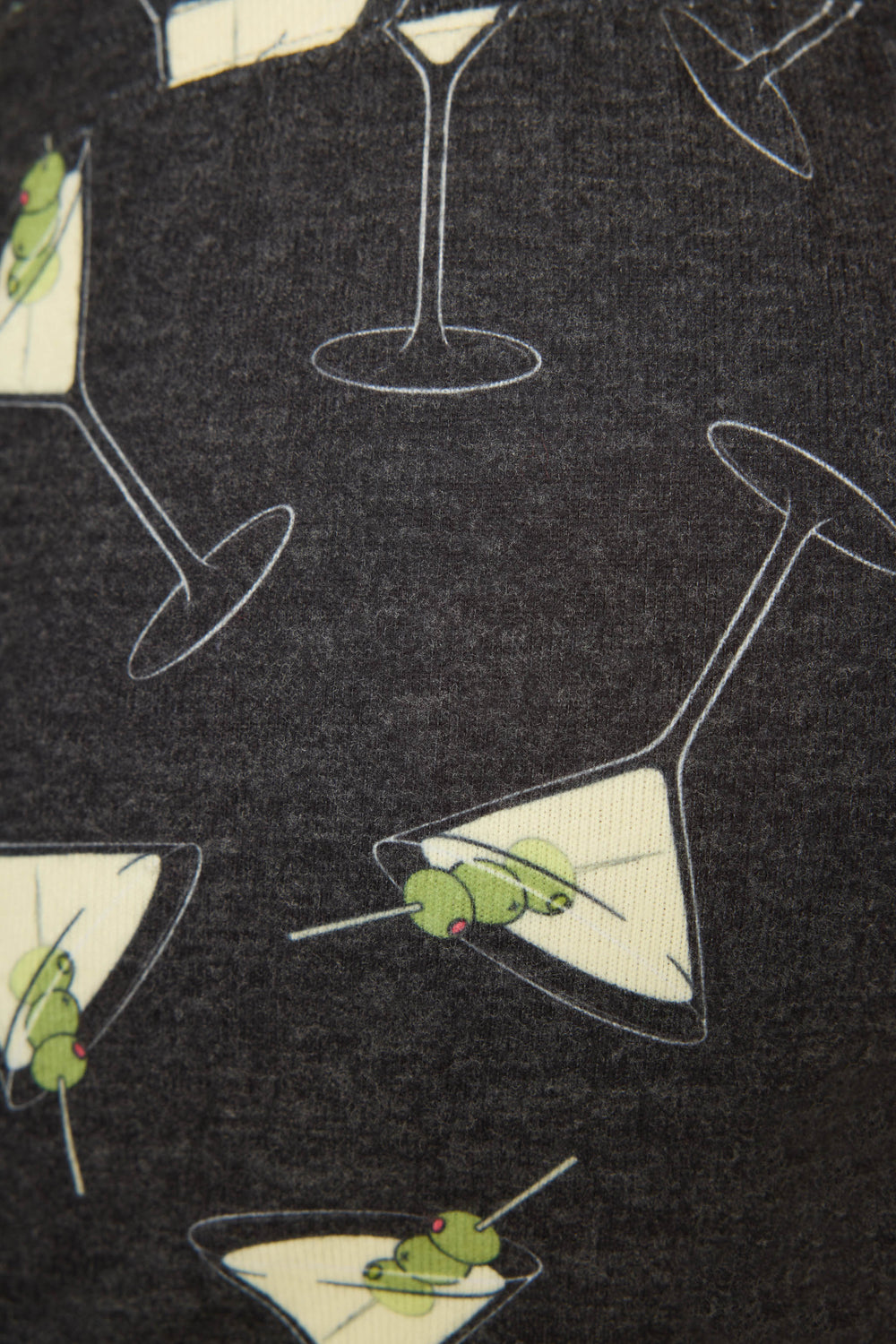 A close-up of the P.J. Salvage Merrier With A Martini Short, featuring dark fabric printed with martini glasses filled with yellow liquid and green olives on toothpicks.
