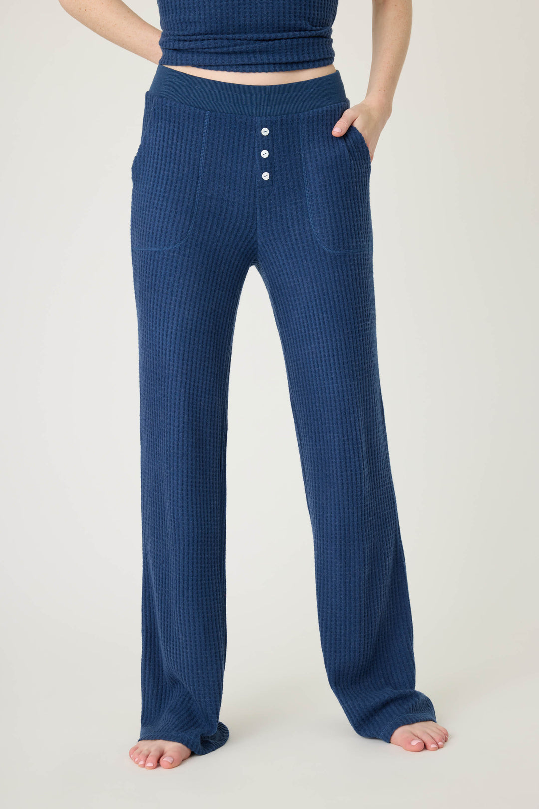 A person models the P.J. Salvage Morning Waffles Solid Navy Open Leg Pant—high-waisted, textured with buttons and pockets—barefoot against a plain light background, showing only their lower torso and legs.