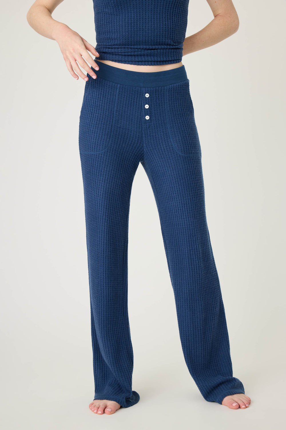 Model wears P.J. Salvage Morning Waffles Solid Navy Open Leg Pant, featuring button detail, paired with a matching navy top; barefoot, standing against a plain light background. Only the lower half of the body is visible.