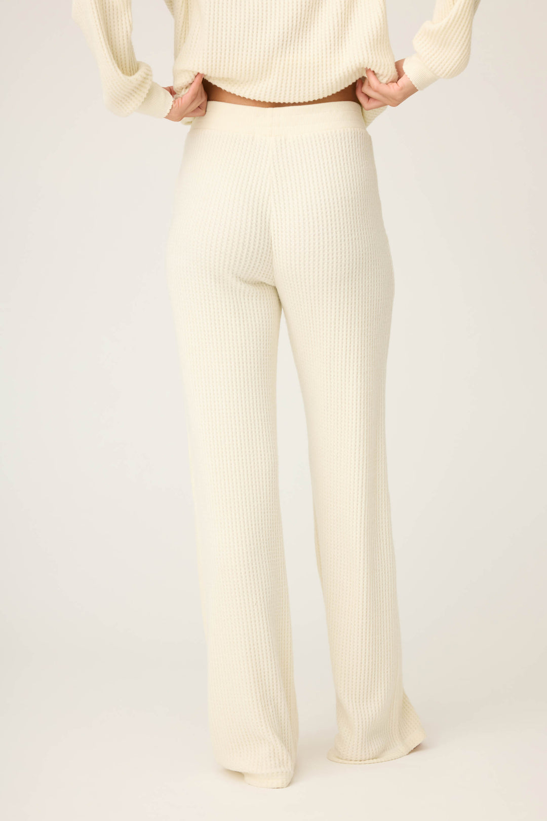 Person wearing P.J. Salvage Morning Waffles Solid Ivory Open Leg Pant, a cream-colored, high-waisted style with a straight-leg fit, paired with a matching top, seen from the back against a plain light background.