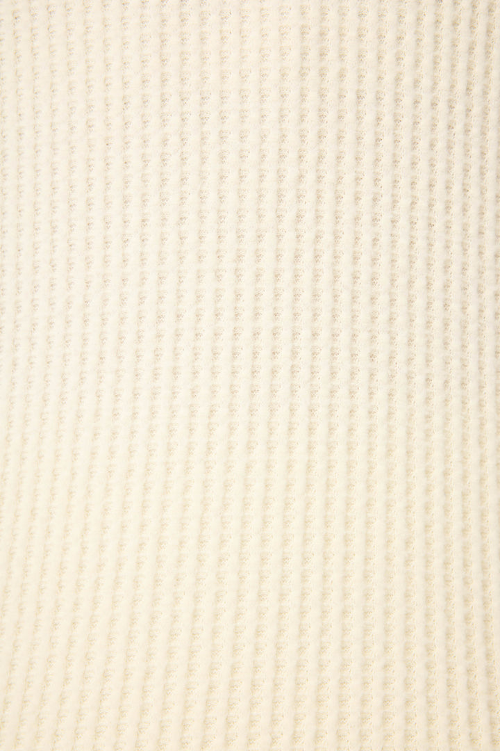 A close-up of the P.J. Salvage Morning Waffles Solid Ivory Open Leg Pant reveals a soft, light beige ribbed fabric with evenly spaced vertical ridges and a slightly fuzzy texture.