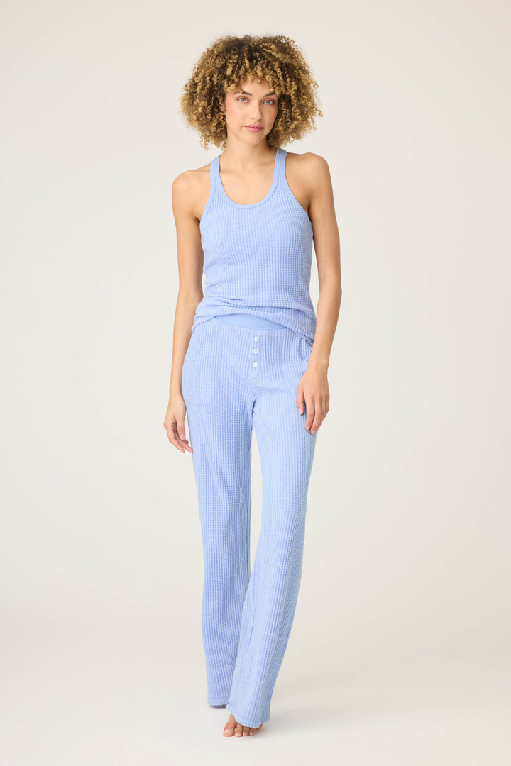 A person stands barefoot against a plain background, wearing the P.J. Salvage Morning Waffles Solid Peri Open Leg Pant with button detail at the waist and a matching ribbed tank top.